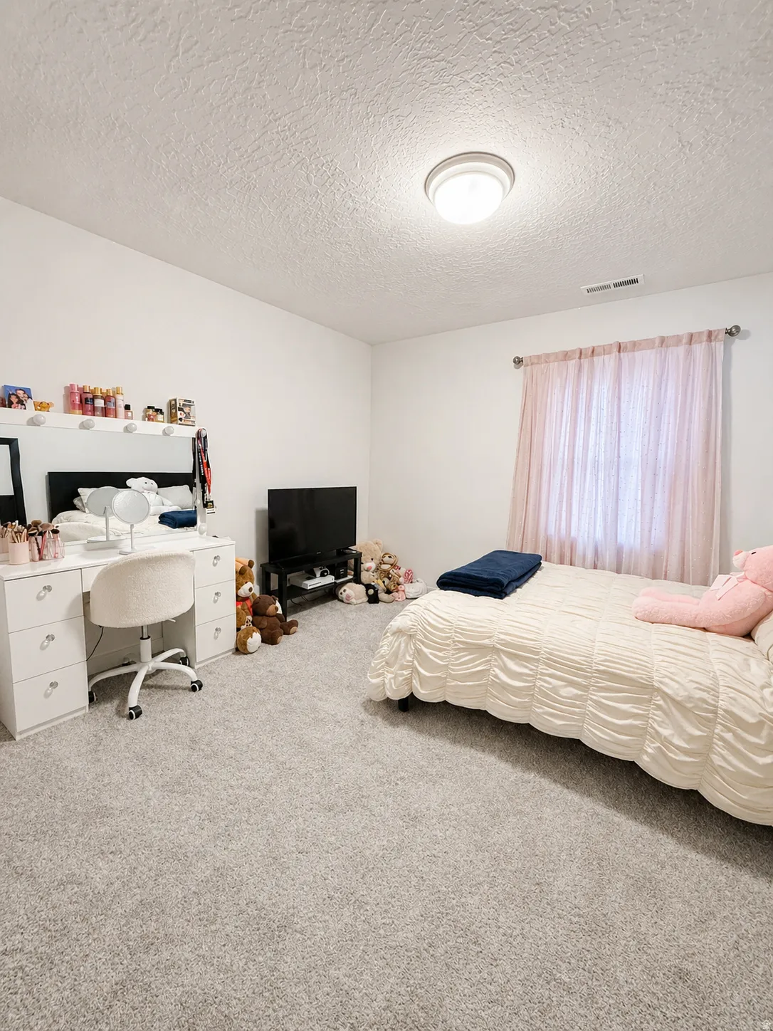 Carpeted bedroom featuring a textured ceiling and a desk