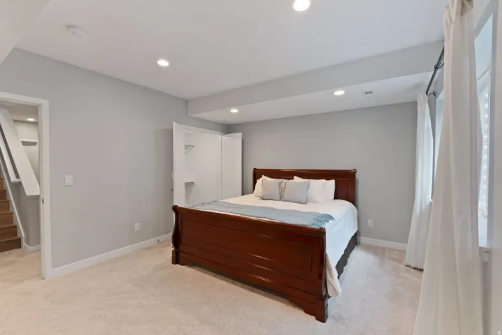 Bedroom with light carpet, recessed lighting, and a walk in closet