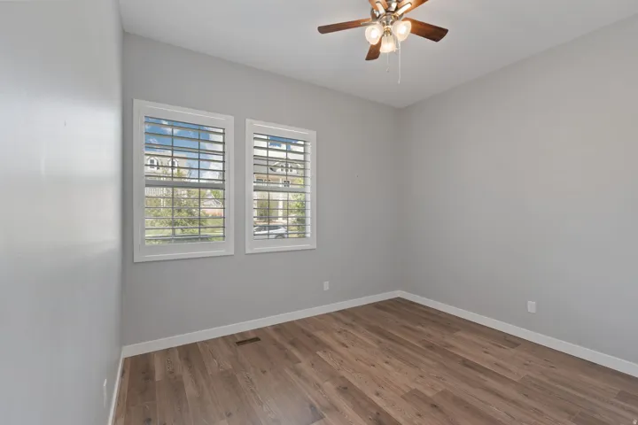 Unfurnished room featuring dark wood-style flooring and a ceiling fan