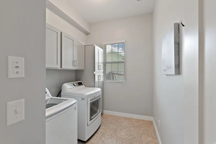 Laundry room with independent washer and dryer, light tile patterned floors, and cabinet space