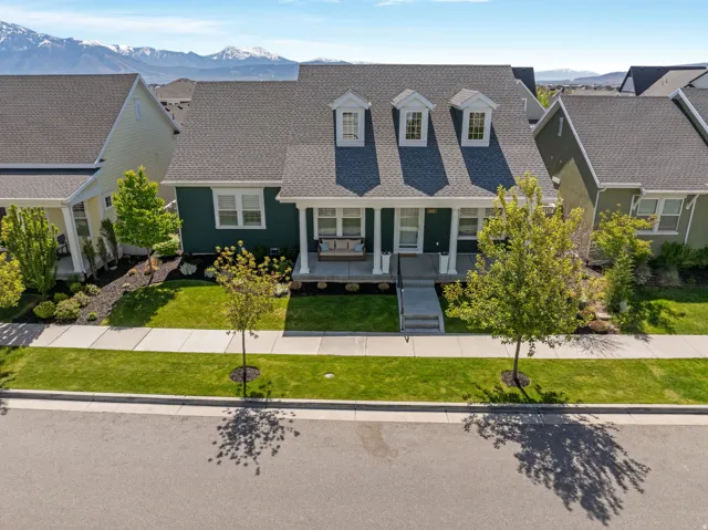 View of front of home featuring a porch, a mountain view, roof with shingles, and a front lawn