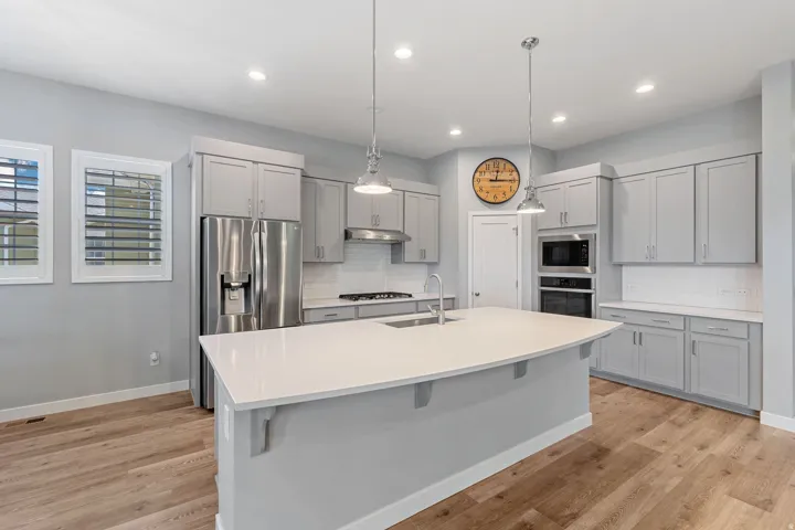 Kitchen with gray cabinetry, stainless steel appliances, pendant lighting, and decorative backsplash