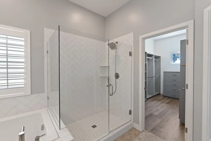 Bathroom featuring a stall shower, a spacious closet, a garden tub, and light wood-style floors