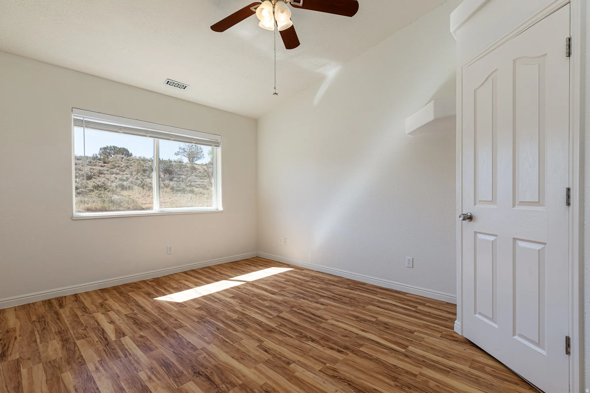 Spare room with lofted ceiling, wood finished floors, and a ceiling fan
