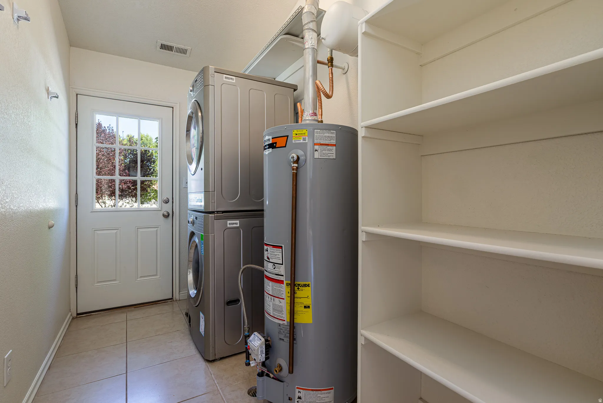 Utilities featuring gas water heater and stacked washing machine and dryer