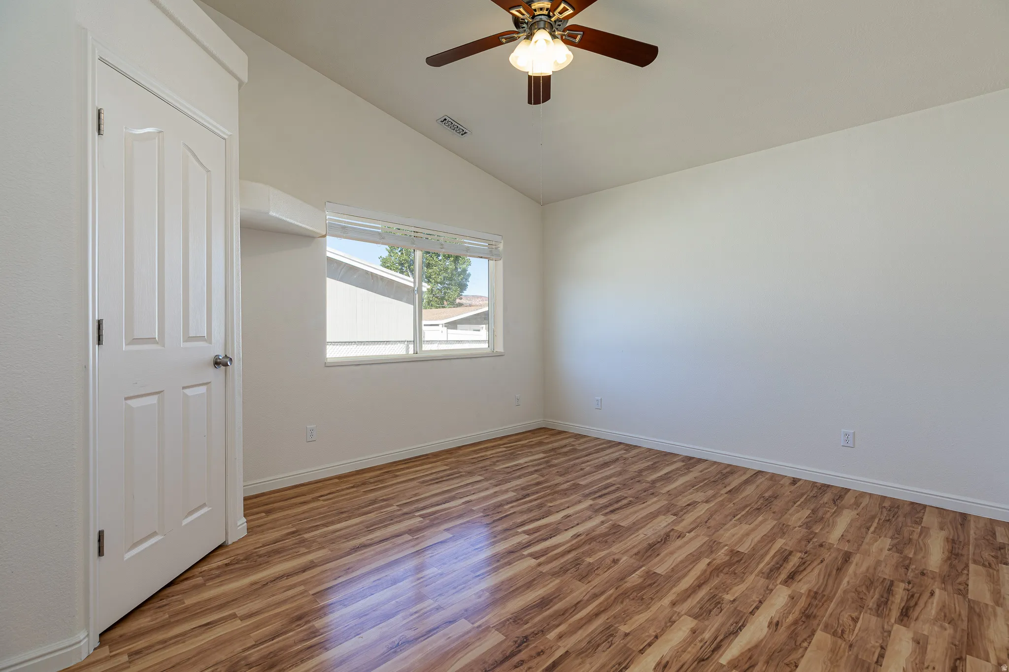 Spare room featuring wood finished floors, a ceiling fan, and lofted ceiling