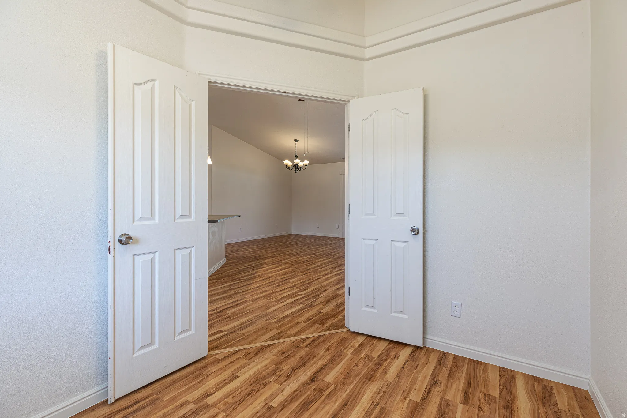 Unfurnished room featuring hanging lights and light wood-style flooring