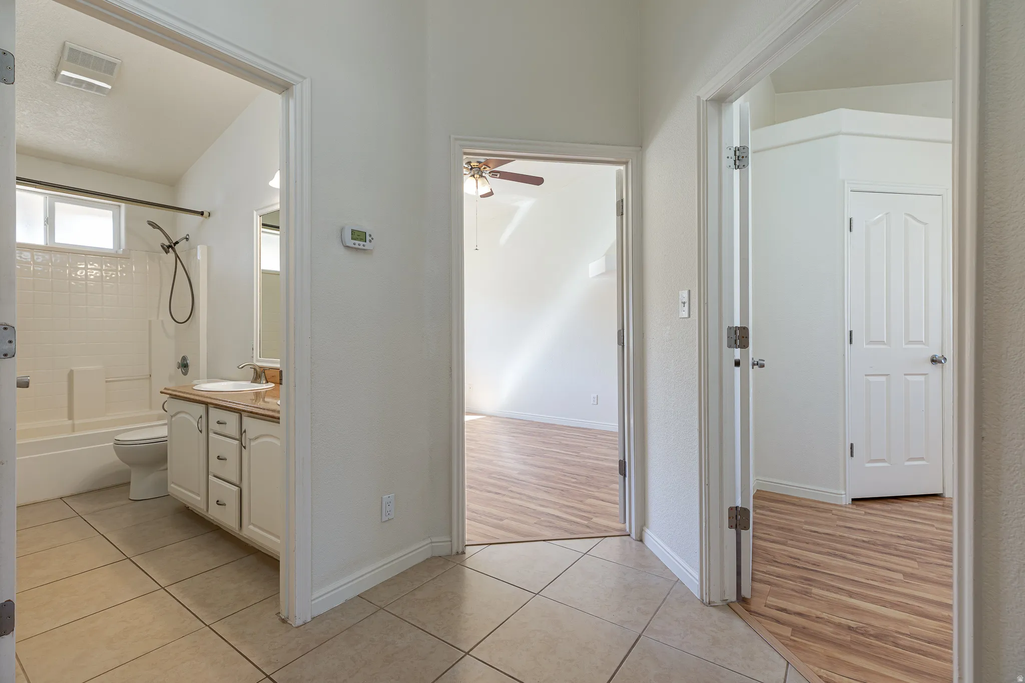 Bathroom with light tile patterned flooring, shower / bath combination, vanity, and a ceiling fan
