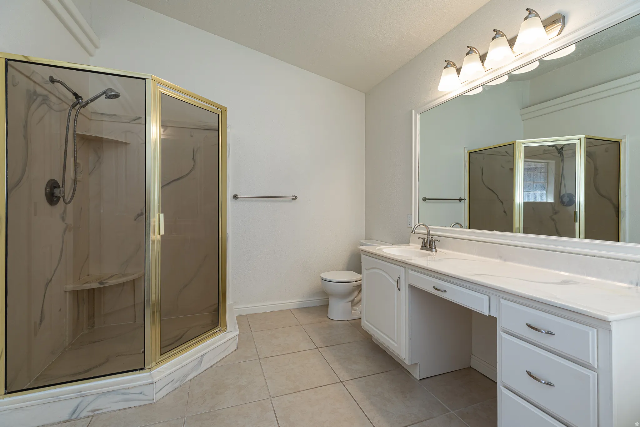 Full bath featuring vanity, a marble finish shower, and light tile patterned floors