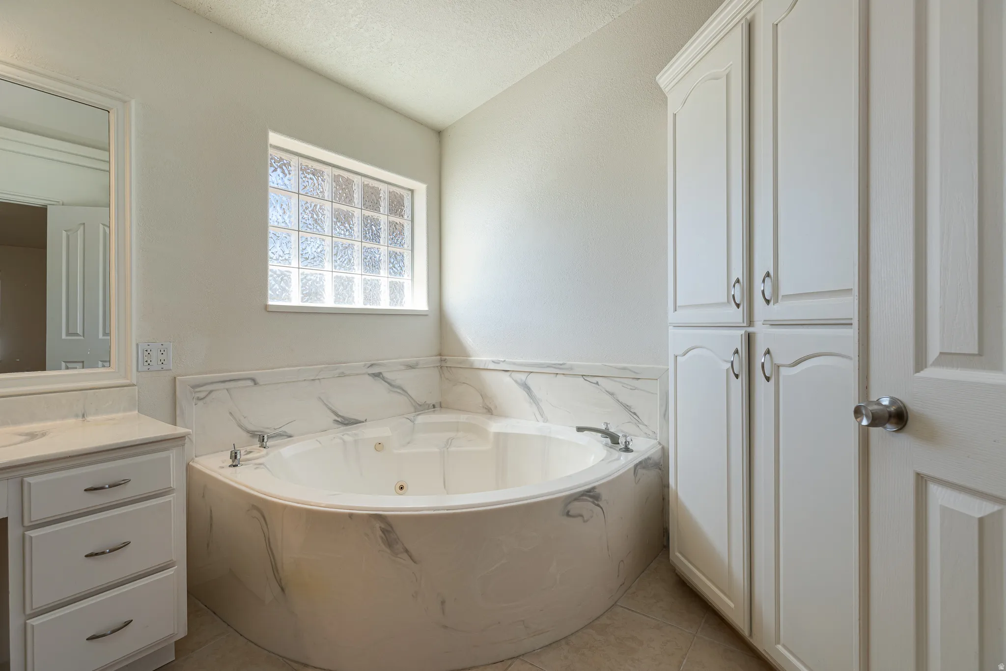 Full bathroom featuring a garden tub, a textured ceiling, vanity, and light tile patterned floors