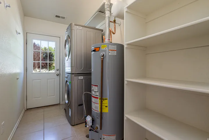 Utilities featuring gas water heater and stacked washing machine and dryer