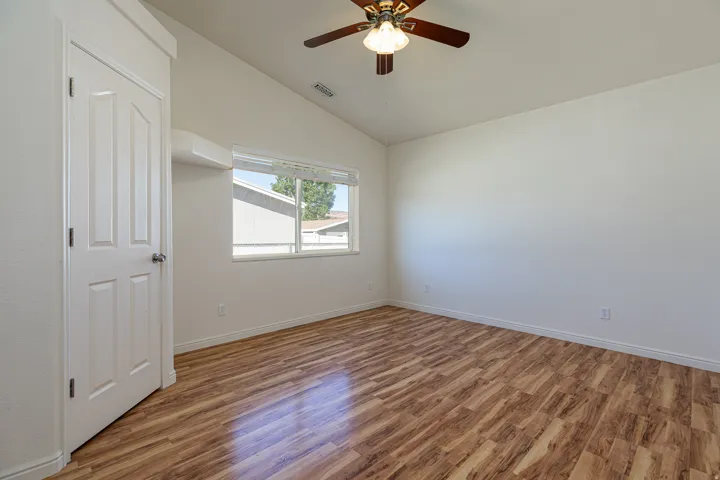 Spare room featuring wood finished floors, a ceiling fan, and lofted ceiling