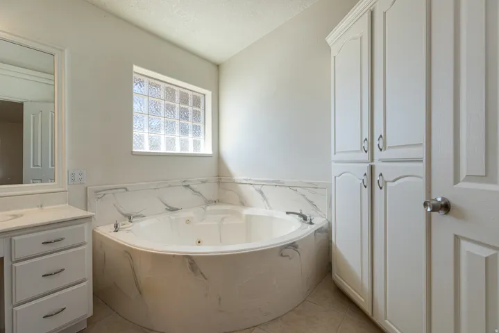 Full bathroom featuring a garden tub, a textured ceiling, vanity, and light tile patterned floors
