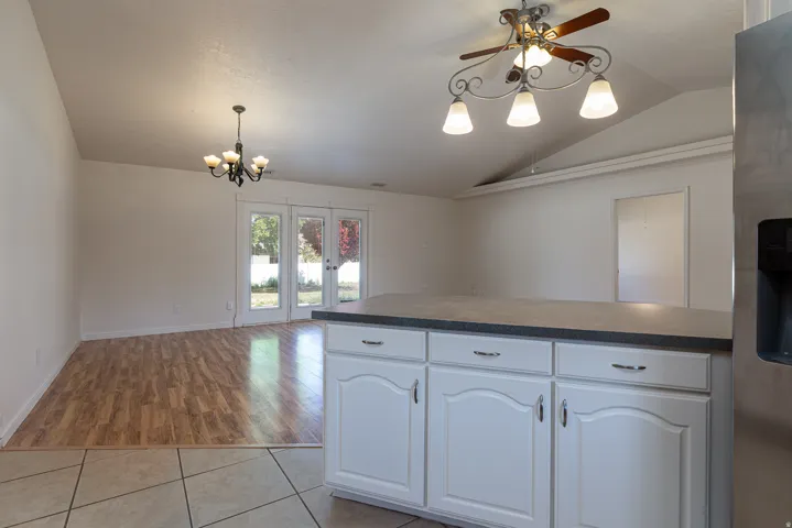 Kitchen with white cabinetry, stainless steel refrigerator with ice dispenser, a ceiling fan, dark countertops, and vaulted ceiling