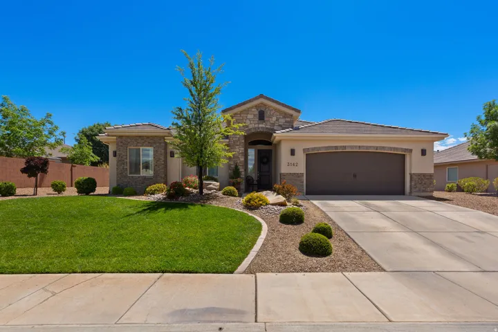 View of front of property featuring stone siding, an attached garage, concrete driveway, and a tiled roof