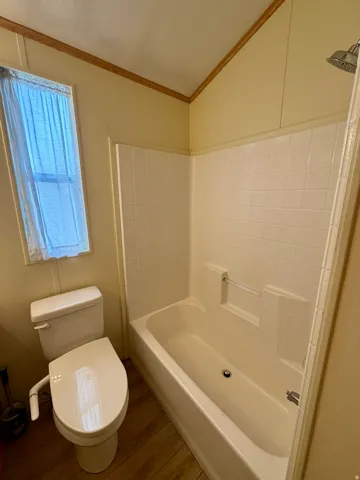 Full bathroom featuring wood finished floors, shower / bathtub combination, and crown molding