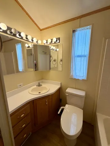 Full bath with crown molding, vanity, dark wood-style flooring, and tub / shower combination