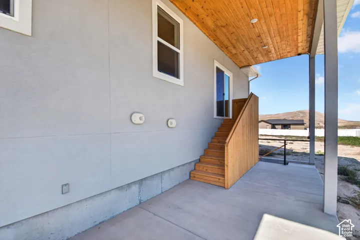 Exterior concrete patio with wood-finish stairs, a wood-finish ceiling, and a sliding glass door