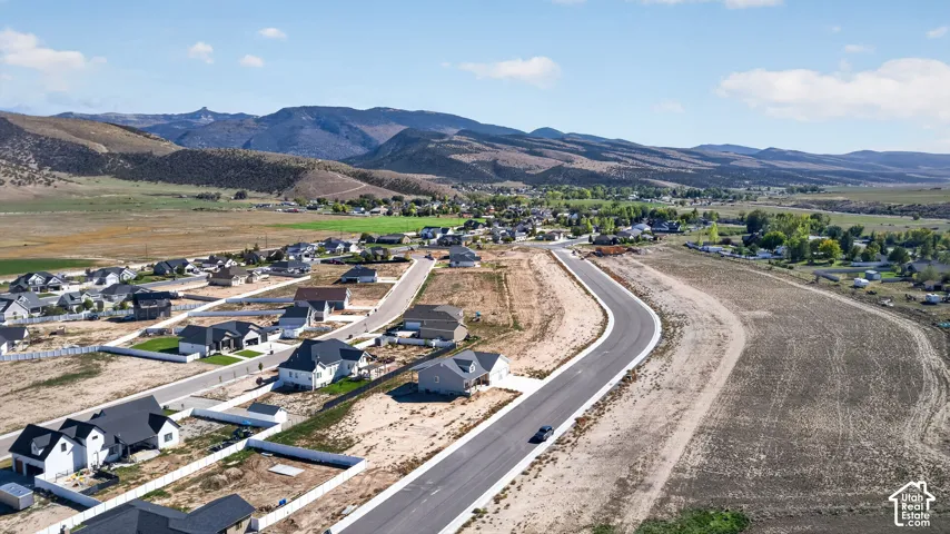 Residential development with paved roads, mountain backdrop, and undeveloped parcels