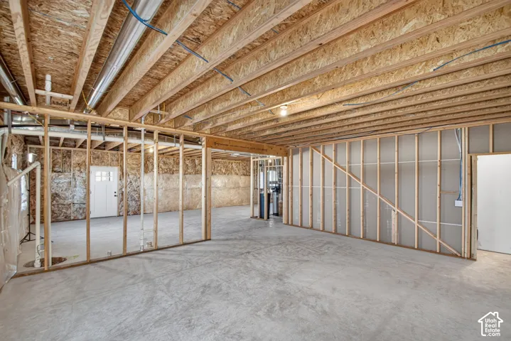 Unfinished basement with exposed ceiling joists, concrete flooring, and framed interior walls