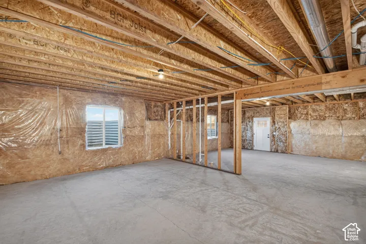 Unfinished basement with exposed ceiling joists, concrete flooring, framed interior walls, and multiple windows