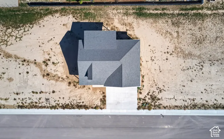 Newly constructed residence with a dark gray shingle roof, concrete driveway, and a paved street