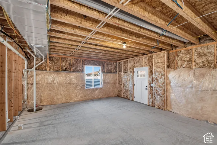 Unfinished basement featuring wood framing, exposed ceiling joists, and a concrete floor