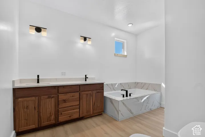 Dual vanity with wood-finish cabinetry, light-toned countertops, and matte black fixtures