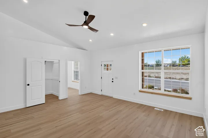 Vaulted ceiling, wood-finish flooring, recessed lighting, ceiling fan, and white paneled doors