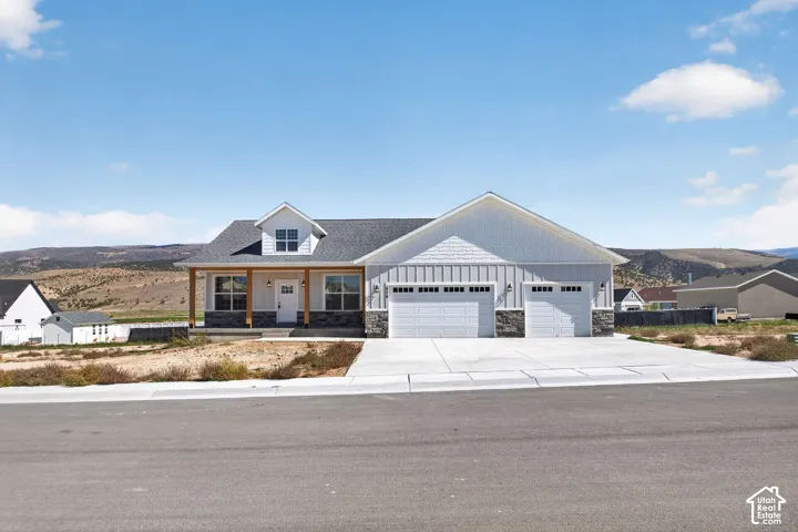 Single-story residence featuring light gray siding, stone accents, and a covered front porch with wood columns