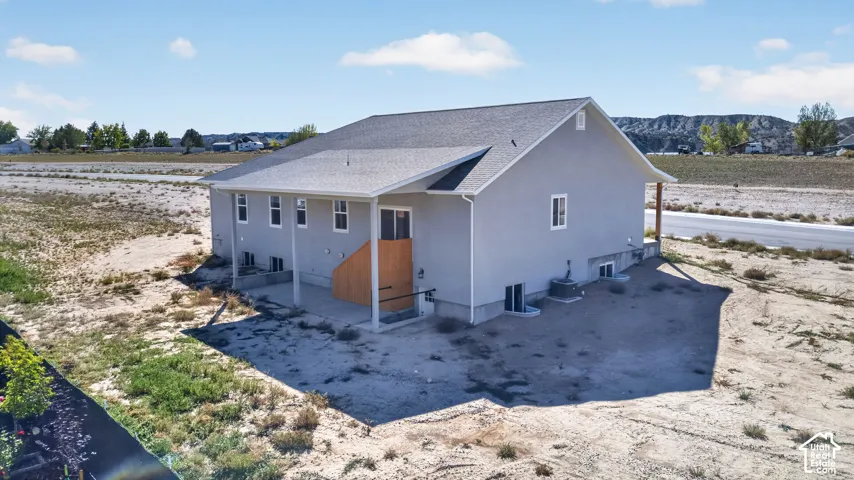 Light gray stucco exterior with a dark gray shingle roof, featuring multiple windows and a sliding glass door