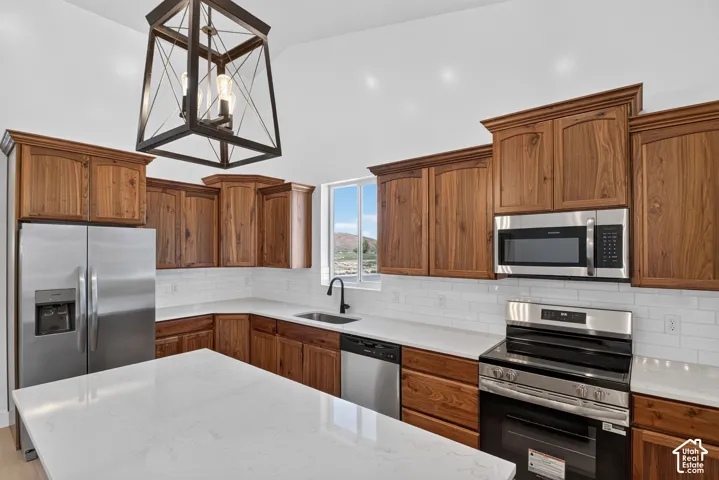 Kitchen featuring wood cabinetry, stainless steel appliances, white subway tile backsplash, and light-toned countertops