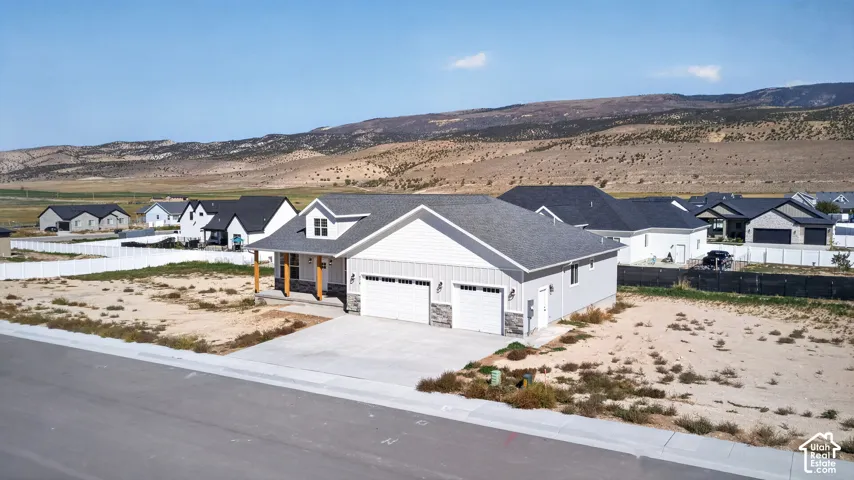 Contemporary home with light gray siding, a dark gray shingle roof, and a two-car garage