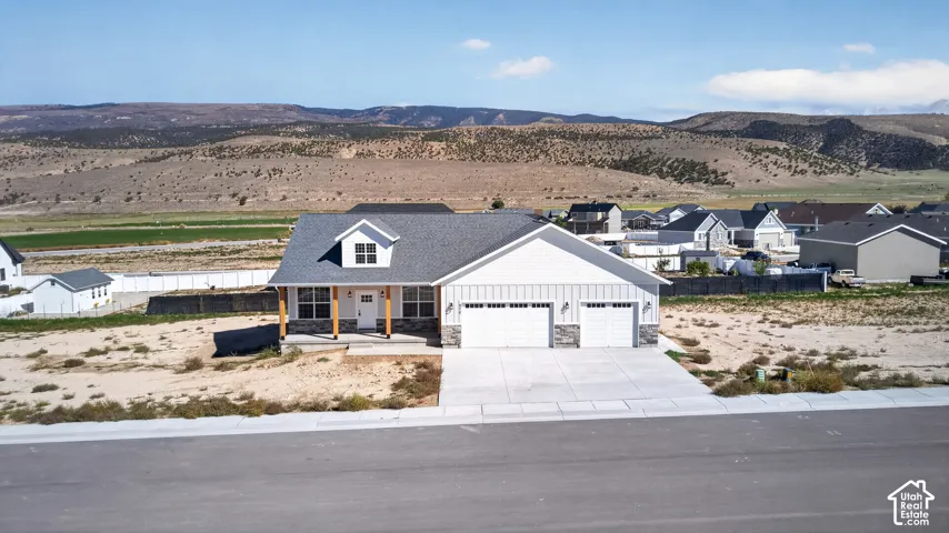 Contemporary residence featuring a two-car garage, dormer window, covered porch entry, and a gravel and rock exterior