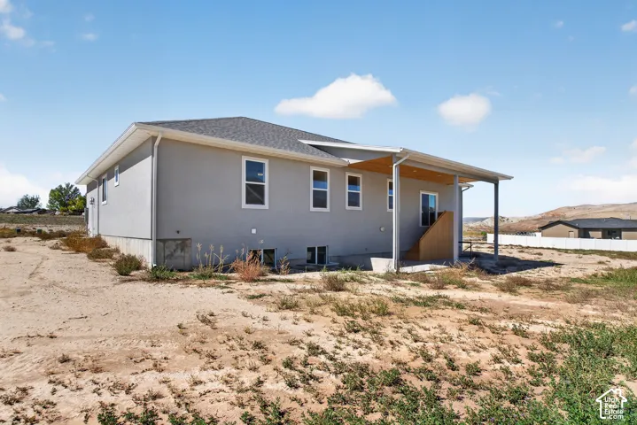 Stucco exterior with a covered patio, exposed wood ceiling detail, and a white perimeter fence