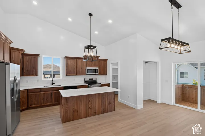 Vaulted ceilings with recessed lighting, wood-finish flooring, and a kitchen island with stone countertops