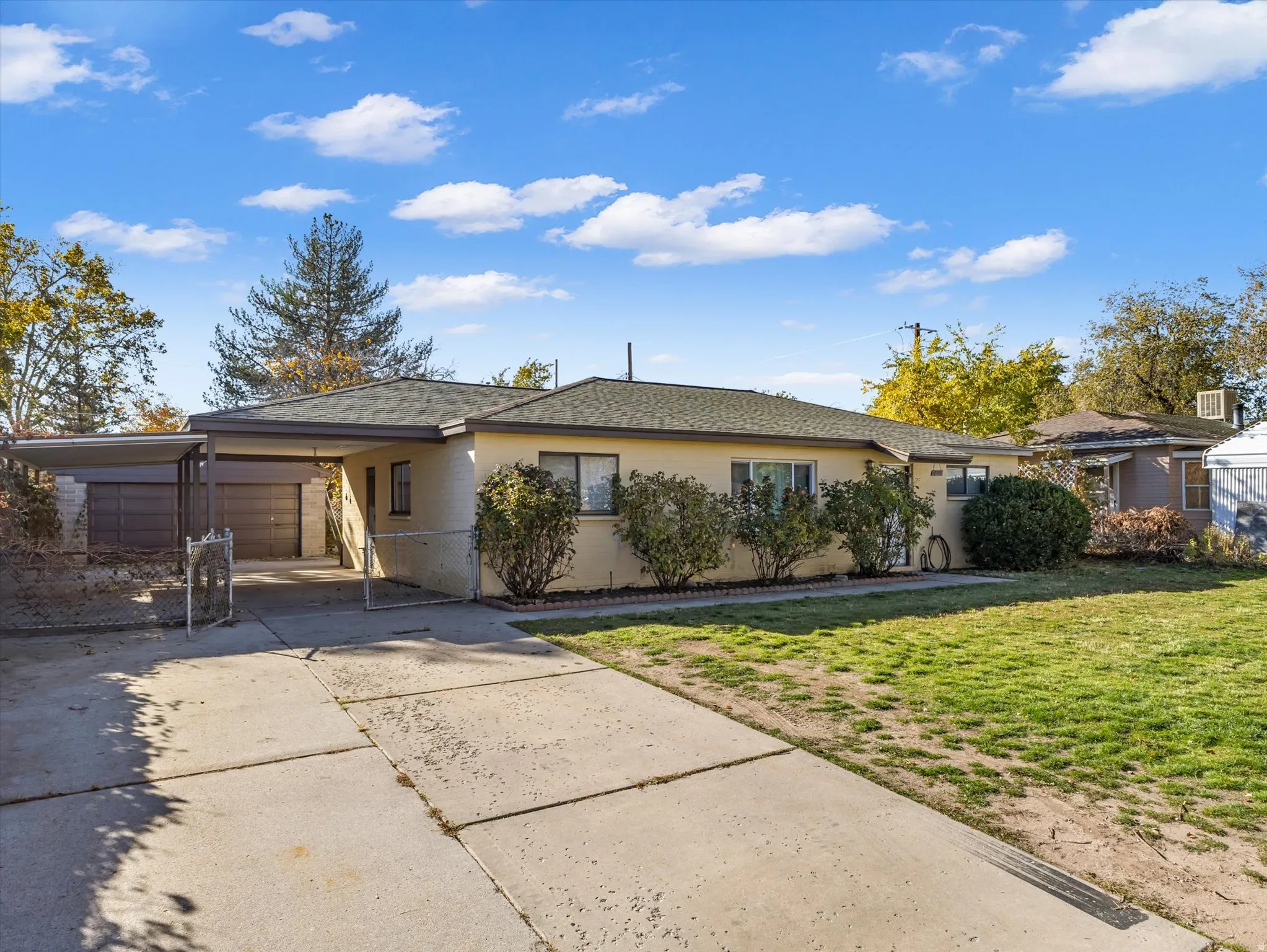Ranch-style home featuring driveway, an attached carport, and roof with shingles