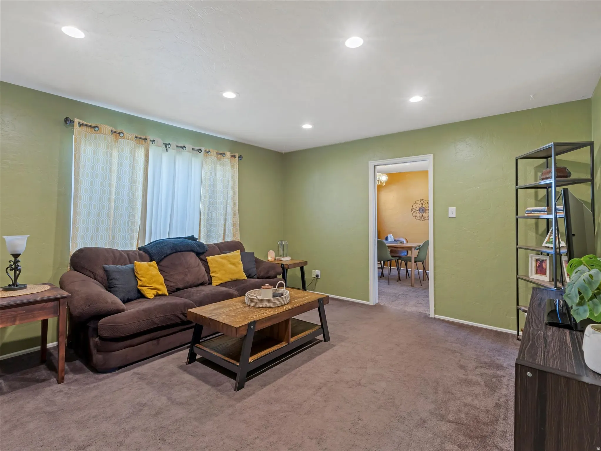 Carpeted living room featuring recessed lighting and a textured wall