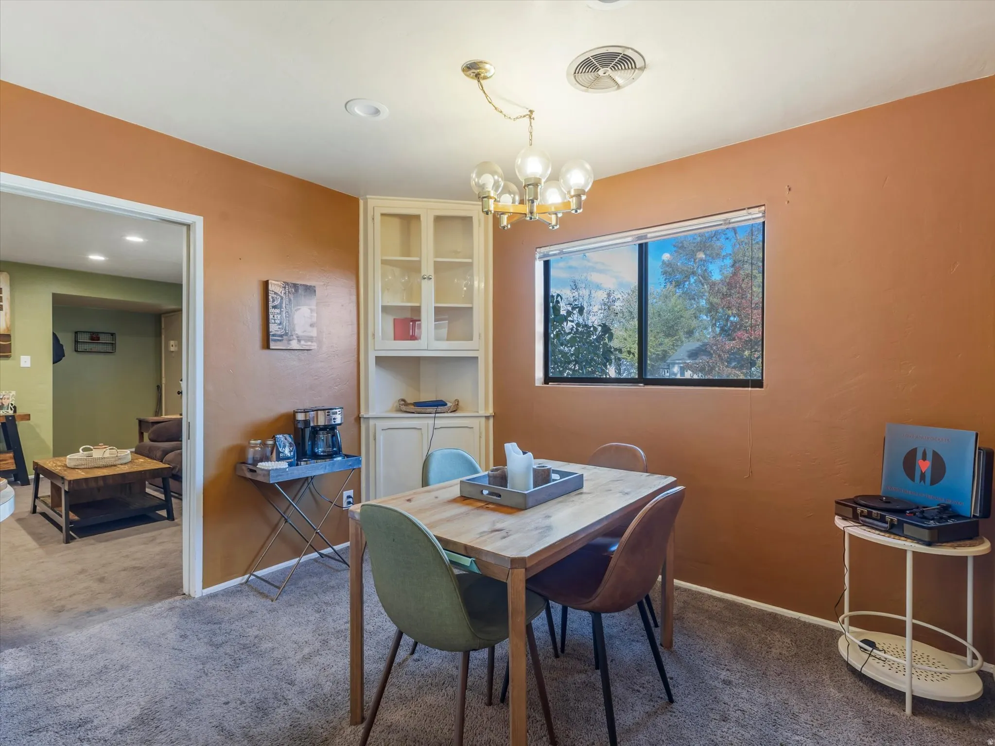 Carpeted dining space featuring suspended lighting and baseboards