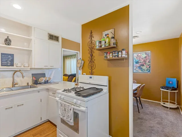 Kitchen featuring open shelves, gas range gas stove, white cabinetry, light countertops, and recessed lighting
