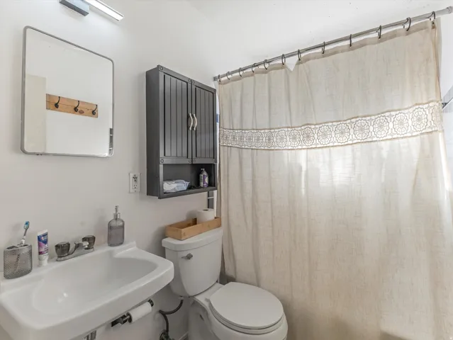 Bathroom featuring a shower with shower curtain and toilet
