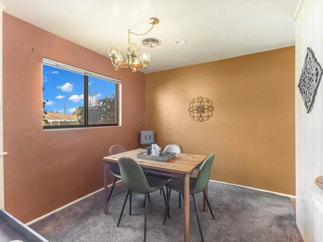 Dining space featuring dark colored carpet and hanging lights