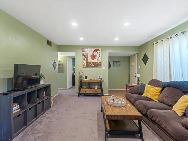 Living area with light colored carpet and recessed lighting