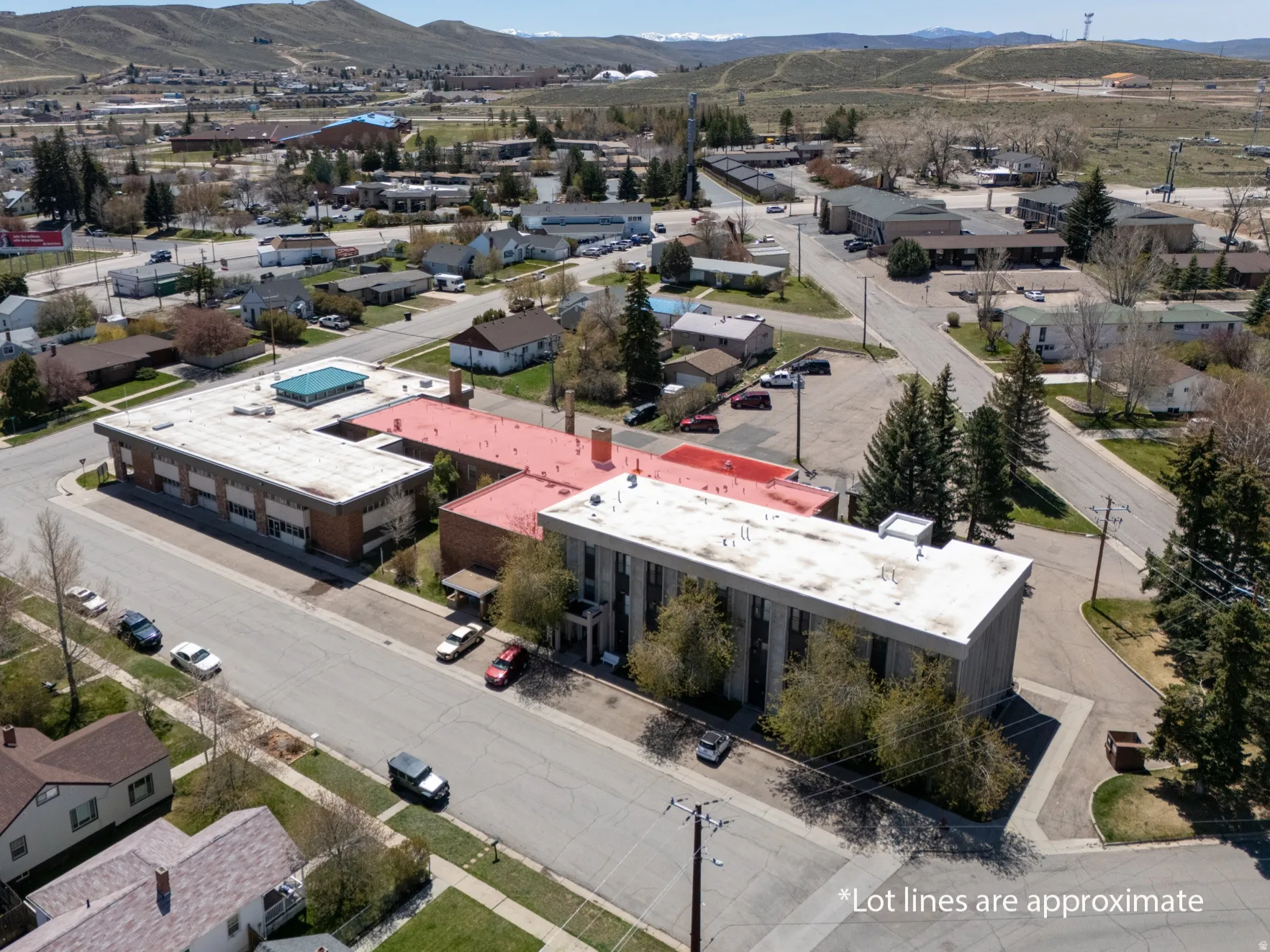 Aerial perspective showcasing two multi-story buildings, one with a red roof and the other with a flat white roof