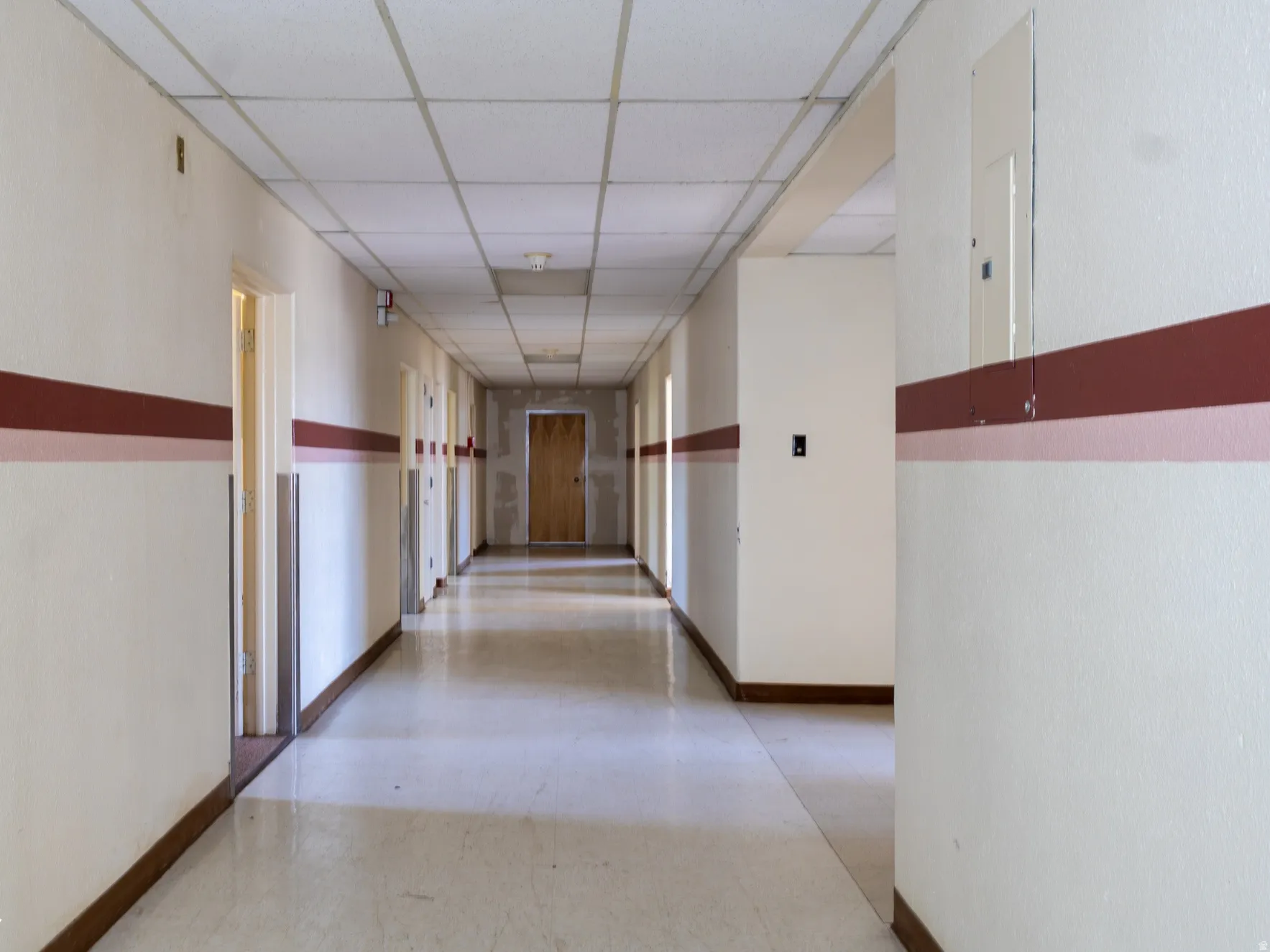 Long hallway with light-colored walls featuring a dual-stripe accent