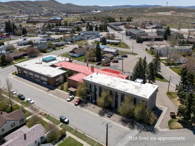 Aerial perspective showcasing two multi-story buildings, one with a red roof and the other with a flat white roof
