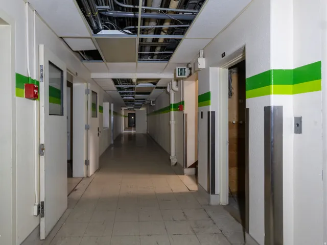 Long corridor with white walls, green striped accents, and a tiled floor
