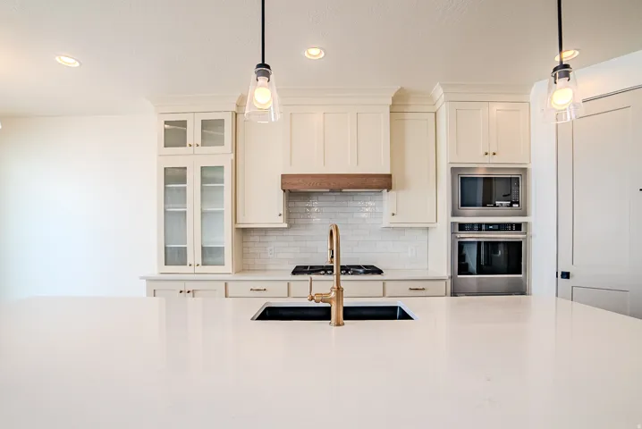 Kitchen with stainless steel appliances, tasteful backsplash, glass insert cabinets, and light stone countertops