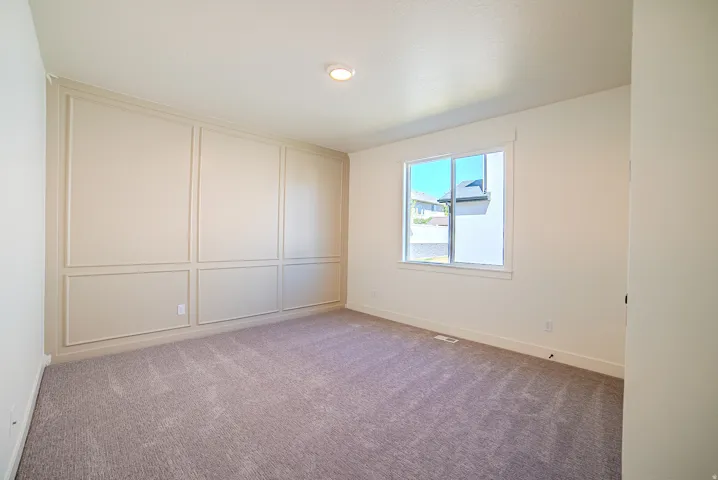 Carpeted spare room with baseboards and a decorative wall