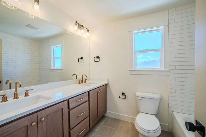 Full bathroom featuring double vanity, light tile patterned flooring, and shower / tub combination